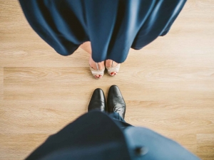 alimony couple standing on wood floor facing each other wearing blue suit and dress